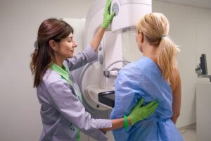 Mammography technologist helps patient with mammogram