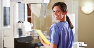 mammography technologist standing in front of machine smiling