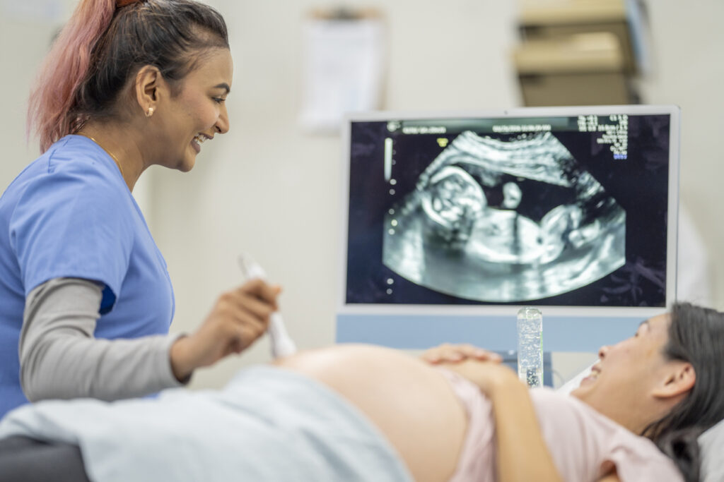 Ultrasound tech performing ultrasound on pregnant patient