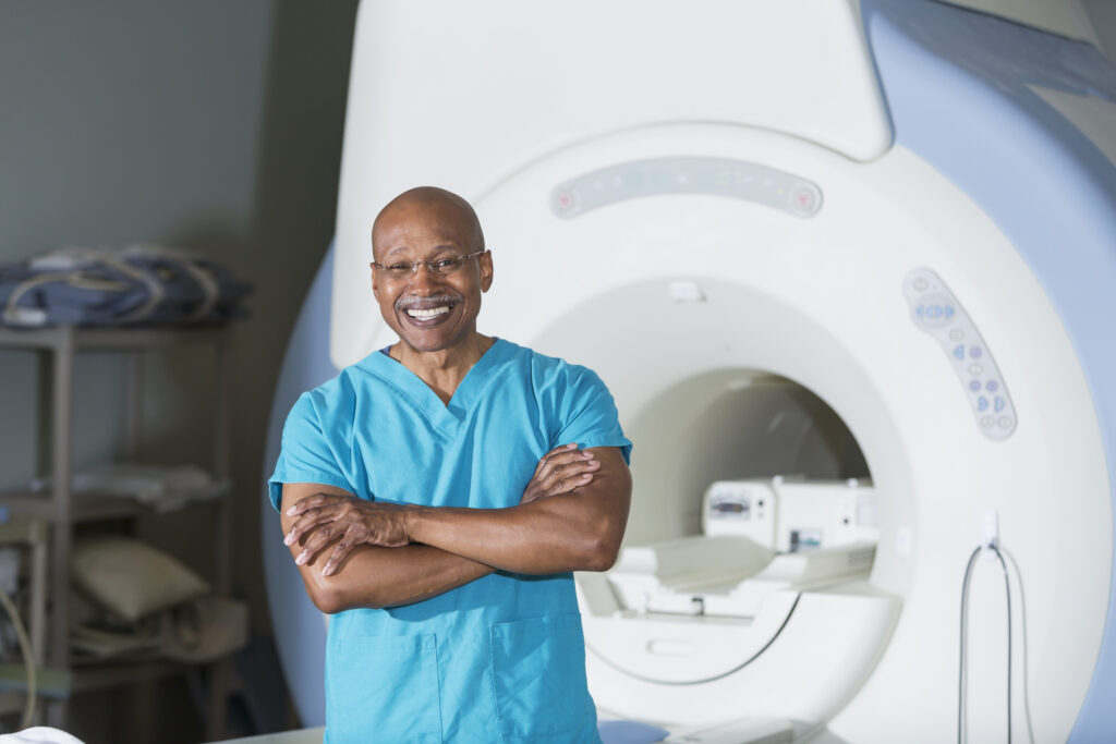 MRI tech smiling in front of scanner
