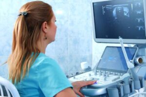 Healthcare worker reviews ultrasound images on screen in hospital setting