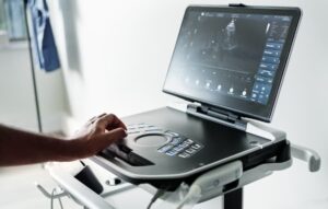Sonographer operating modern ultrasound machine with heart image on screen