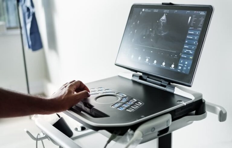 Sonographer operating modern ultrasound machine with heart image on screen